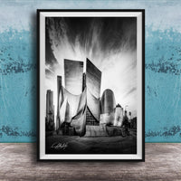 A black and white photograph of a modern, curved building with a distinctive architectural design, set against a cloudy sky.