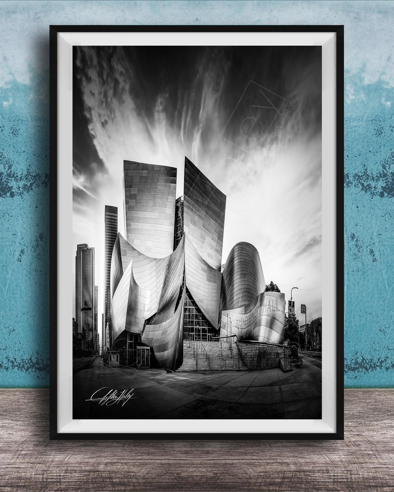 A black and white photograph of a modern, curved building with a distinctive architectural design, set against a cloudy sky.
