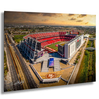 An aerial view of a large sports stadium, likely the San Francisco 49ers stadium, with the surrounding cityscape and a cloudy sky in the background.