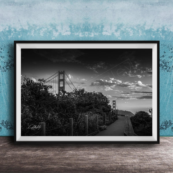 A black and white photograph of the Golden Gate Bridge in San Francisco, California, with a cloudy sky in the background.
