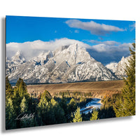 A breathtaking mountain landscape with snow-capped peaks, a winding river, and a lush forest in the foreground.