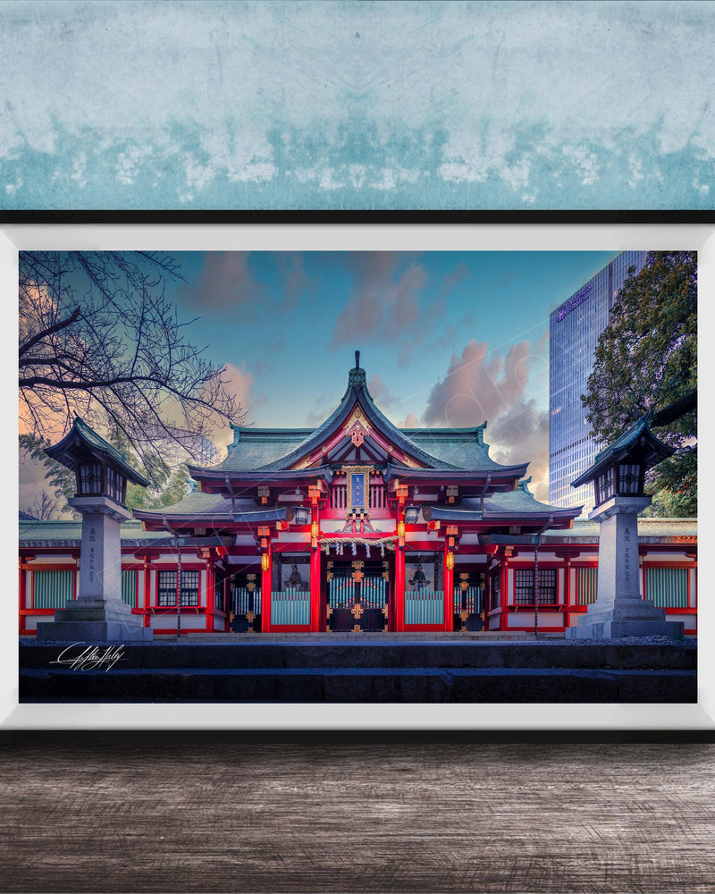 A framed photograph of a traditional Japanese temple with a red roof and white walls, set against a blue sky with clouds.