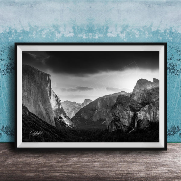 A black and white photograph of a mountainous landscape, with dramatic clouds and a waterfall in the foreground.