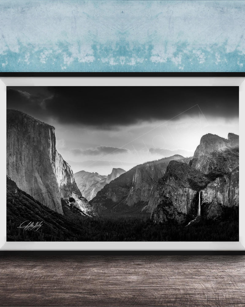 A black and white photograph of a mountainous landscape, with dramatic clouds and a waterfall in the foreground.