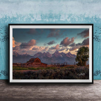 a rustic wooden barn nestled in a grassy field, with majestic mountains in the background under a vibrant sky.