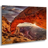 a breathtaking view of a natural arch formation, with the sun's rays shining through the opening and illuminating the surrounding landscape.