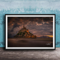 A framed photograph of the iconic Mont Saint-Michel in Normandy, France, with a dramatic sky in the background.