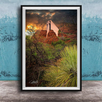 a framed photograph of a desert landscape with a large, white structure in the background, possibly a building or monument, set against a dramatic sky with clouds and a sunset.