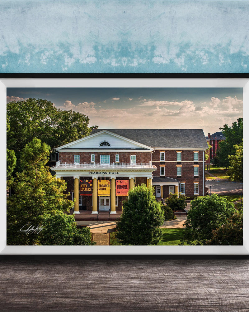A framed photograph of the Peabody Hall building, a historic brick structure with a prominent pediment and columns, surrounded by trees and a blue sky.