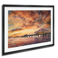 a serene scene of a wooden pier extending into a calm body of water, with a building on the pier and a vibrant sunset sky in the background.