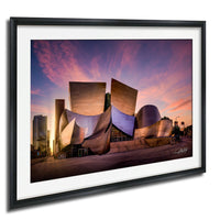 a modern, futuristic building with a unique, angular design set against a vibrant sunset sky.