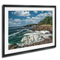 a rocky coastline with crashing waves, surrounded by a blue sky with white clouds.