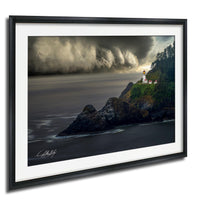 A framed photograph depicting a lighthouse on a rocky coastline, with a stormy sky and crashing waves in the background.