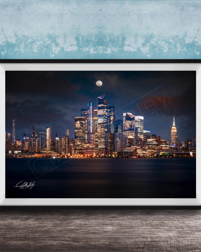 A framed photograph of the New York City skyline at night, with the city's iconic landmarks illuminated against a dark sky.