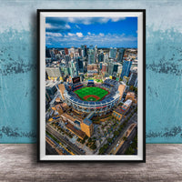 An aerial view of a baseball stadium surrounded by a city skyline, with tall buildings and a clear blue sky in the background.