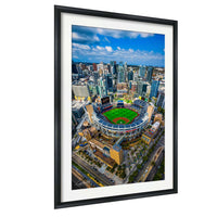 An aerial view of a baseball stadium surrounded by a cityscape, with tall buildings and a clear blue sky in the background.