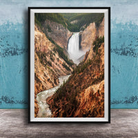 A framed photograph of a majestic waterfall cascading down a rugged, mountainous landscape.