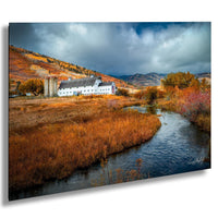 A picturesque rural landscape with a white barn nestled among the rolling hills, a stream meandering through the foreground, and a dramatic sky filled with clouds.
