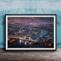 The image is a framed aerial view of a city at night, showcasing a bridge and the city skyline with illuminated buildings and a river.
