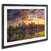 a city skyline at sunset, with the tall buildings reflected in the water below.