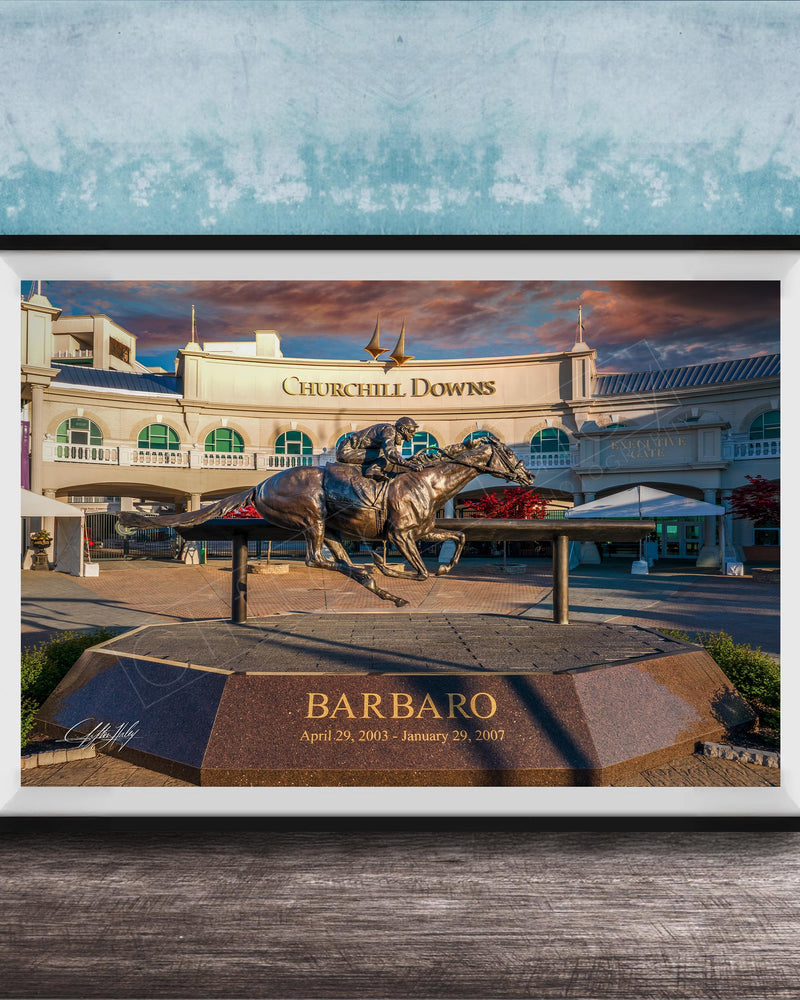 A bronze statue of a horse and jockey racing on a track, with the name "Barbario" displayed below the statue. The background shows a large building with the name "Churchill Downs" written on it.