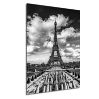 The image is a black and white photograph of the Eiffel Tower in Paris, France, with a cloudy sky in the background.