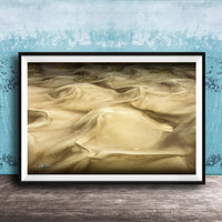 The image is a framed photograph of sand dunes, with a blue wall in the background.
