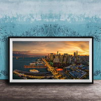 The image is a framed photograph of a cityscape at sunset, featuring a skyline with tall buildings and a harbor with boats.