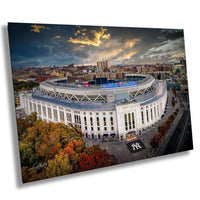 a large, circular stadium with a curved roof, surrounded by trees and buildings in the background. The sky above the stadium is cloudy, and the sun is setting, creating a dramatic and colorful atmosphere.