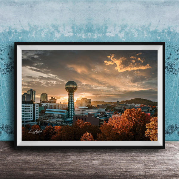 a city skyline at sunset, with a large tower in the center and a colorful sky in the background.