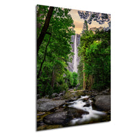 A serene waterfall cascades through a lush, green forest, surrounded by towering trees and rocky terrain.