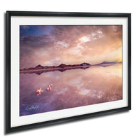 a serene landscape with a calm lake reflecting the vibrant colors of the sky, surrounded by mountains.