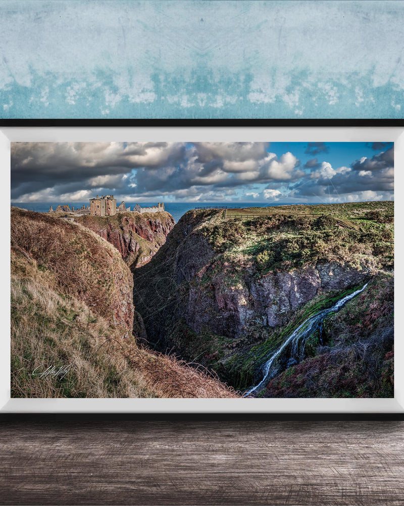 The image is a framed photograph depicting a scenic landscape with a waterfall cascading down a steep cliff face. The photograph is set against a blue wall, creating a striking contrast with the natural elements. The image showcases the beauty of the outdoors and the power of nature.