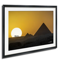a desert landscape with a pyramid in the background and a camel caravan in the foreground, set against a vibrant yellow and orange sunset sky.