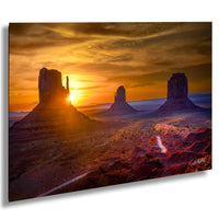 a breathtaking desert landscape at sunset, with three large rock formations silhouetted against the vibrant orange and yellow sky.