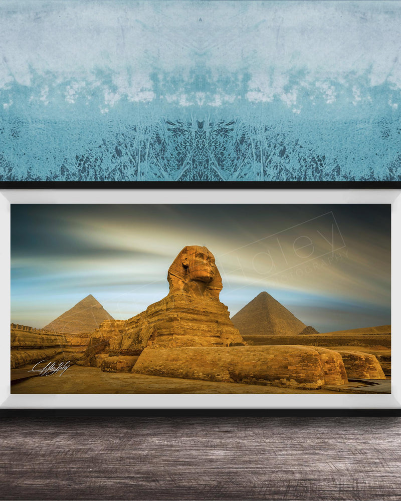 a framed photograph of the Great Sphinx of Giza, a large limestone statue of a mythical creature, in front of the pyramids of Giza in Egypt.