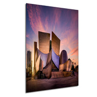 a modern, curved building with a unique architectural design, set against a vibrant sunset sky.