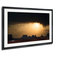 a dramatic sunset over a desert landscape, with silhouetted mountains in the background.
