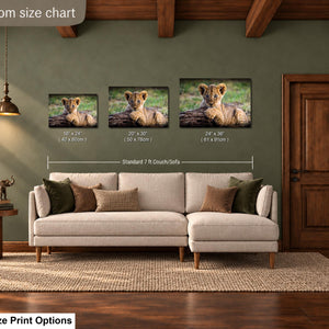 a living room with a large sofa, a wooden door, and a lamp. There are three framed photographs of a young lion cub displayed on the wall above the sofa. The wall is painted in a green color, and the room has a wooden floor.