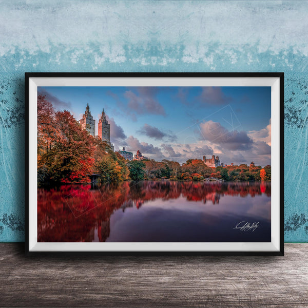 A framed photograph of the New York City skyline, with the city's iconic landmarks and trees reflected in the water below.