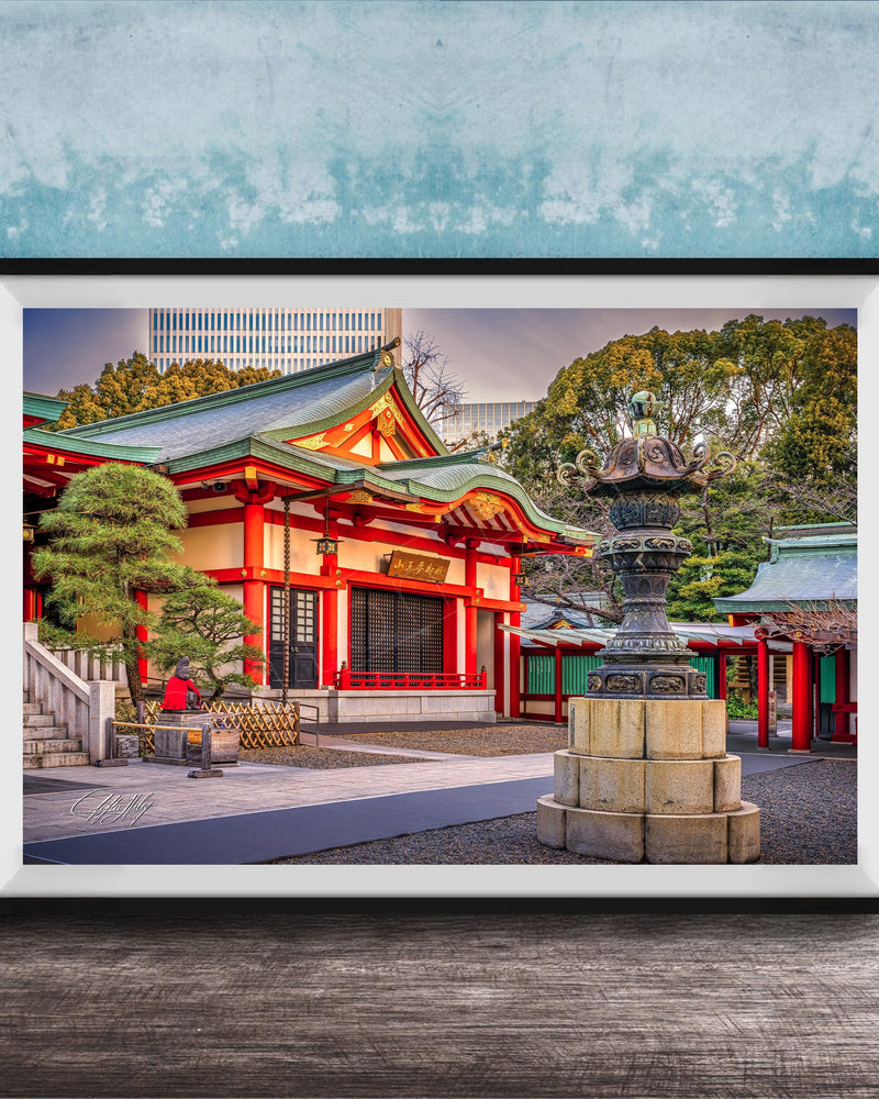 A framed photograph of a traditional Japanese temple with a red roof and white walls, surrounded by trees and a stone fountain.