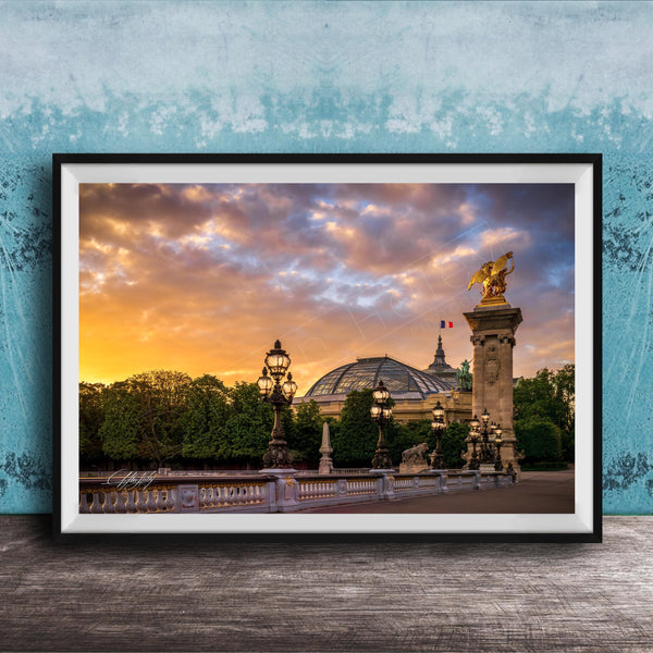 a picturesque scene of a cityscape with a large domed building, ornate lampposts, and a statue of a winged figure, all set against a vibrant sunset sky.