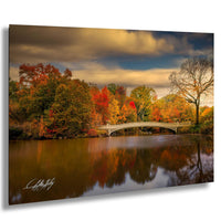 a serene autumn landscape with a white bridge spanning a calm body of water, surrounded by vibrant trees with red, orange, and yellow foliage.