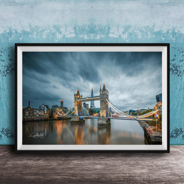 A framed photograph of the iconic Tower Bridge in London, England, with the bridge illuminated against a cloudy sky.