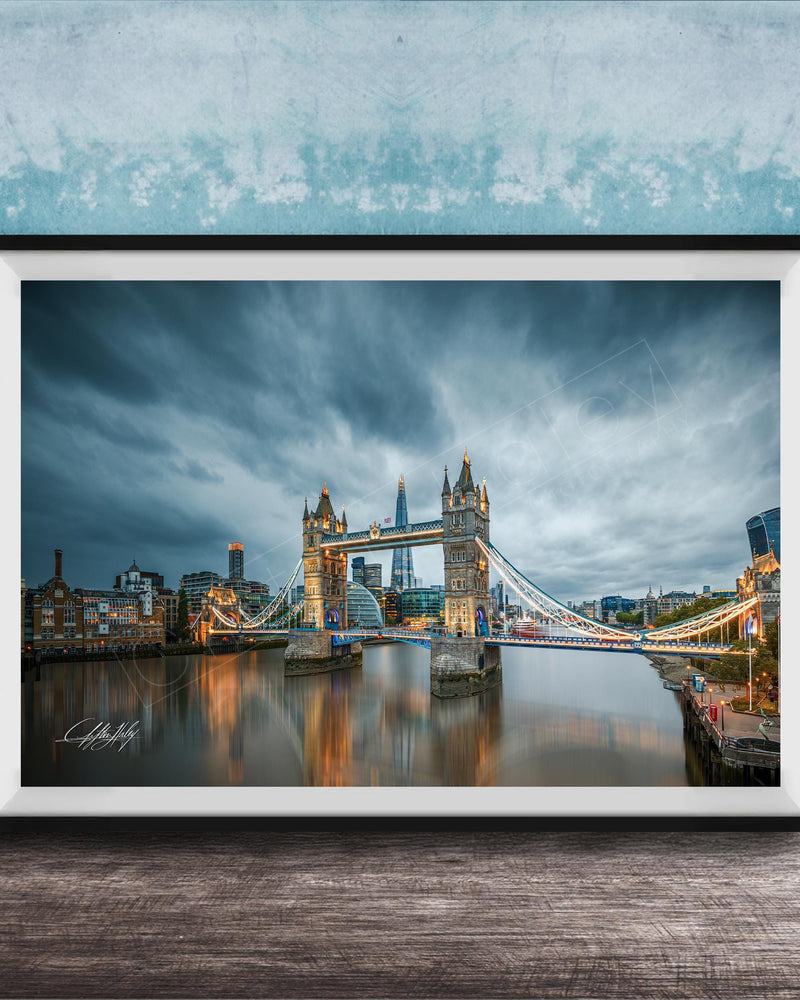 A framed photograph of the iconic Tower Bridge in London, England, with the bridge illuminated against a cloudy sky.