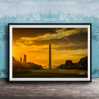 the Washington Monument at sunset, with the tall obelisk silhouetted against a vibrant orange and yellow sky.