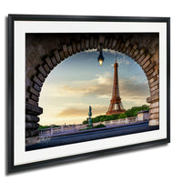 a framed photograph of the Eiffel Tower in Paris, France, with a stone archway framing the view of the iconic landmark.