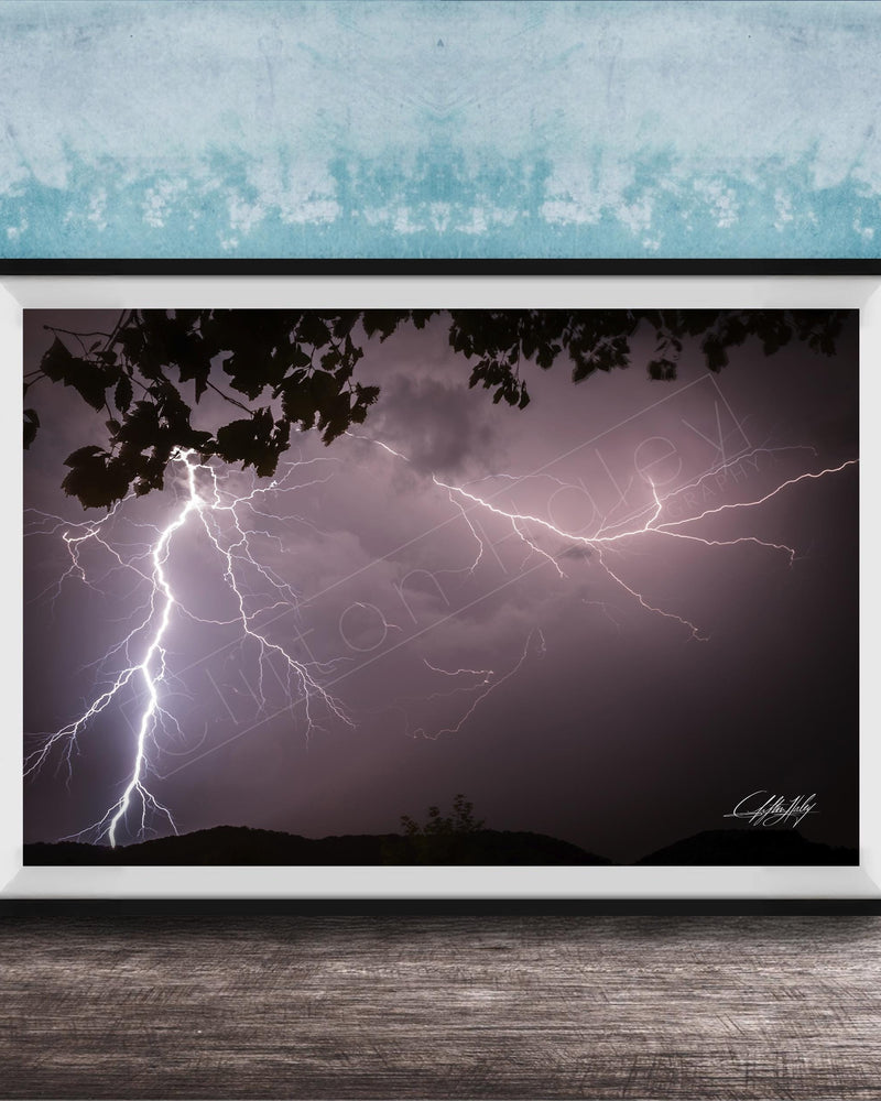 A framed photograph of a dramatic lightning storm with bolts of light illuminating the dark sky.