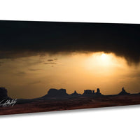 a dramatic sunset over a desert landscape, with silhouetted mountains in the background and a dramatic cloud formation in the sky.