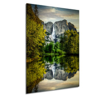 a serene landscape with a large waterfall cascading down a rocky cliff, surrounded by lush green trees and reflected in a calm lake below.